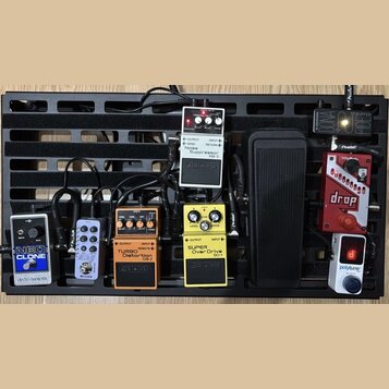 Černý pedálboard s několika efektovými pedály. Jsou zde pedály Electro-Harmonix NEO CLONE, MODER, BOSS TURBO Distortion DS-2, BOSS SUPER OverDrive SD…