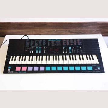 Černý elektronický klávesový nástroj s bílými a černými klávesami. Na horním panelu je nápis Music STATION, digitální displej zobrazující hodnoty 0.0…