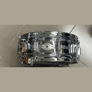 Chromovaný snare drum s kovovým korpusem. Na přednímstěně je oválný štítek s nápisy DYNA-SONIC, SERIAL NO. a CUSTOM BUILT. Nástroj vykazuje známky po…