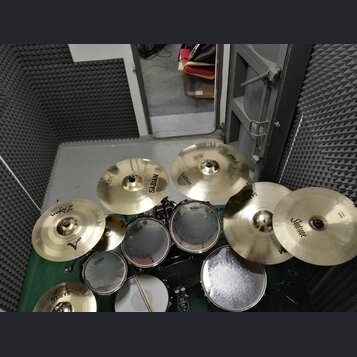 Sada cymbálů a bubnů v zeleném provedení. Na cymbálech jsou viditelné nápisy SABIAN, Zildjian a Soultone. Bubny mají bílé koženky s logem Evans. Celý…