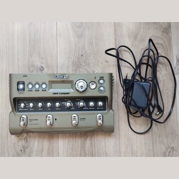 Zelený looper Line 6 JM4 Looper s kovovým šasi a ovládacími prvky. Na předním panelu jsou čtyři spínače, displej a řada otočných potenciometrů s nápi…