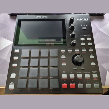 Černý sampler MPC ONE značky AKAI PROFESSIONAL s integrovaným displejem. Zařízení obsahuje 16 gumových padů, několik ovládacích knofíků a řadu progra…