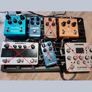 Na černém pedalboardu je umístěno šest efektových pedálů. V horní řadě jsou zleva modrý pedal s nápisy „blueSky“ a „strymon“, modrý pedal s nápisy „F…