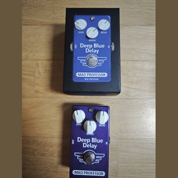 Dvě efektové pedály Deep Blue Delay značky MAD PROFESSOR, BJF DESIGN. Horní pedál je v černém kovovém boxu s modrým ovládacím panelem, spodní pedál m…