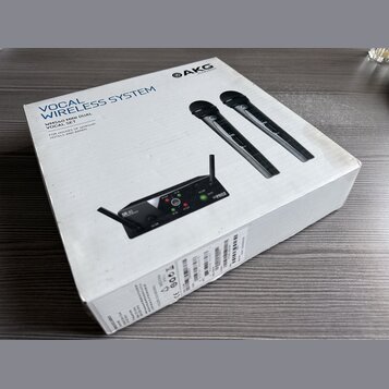Bílá kartonová krabice s nápisy VOCAL WIRELESS SYSTEM a WMS40 MINI DUAL VOCAL SET. V horní části je logo AKG HARMAN, na obrázku jsou dva černé bezdrá…