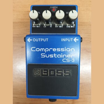 Modrý efekt pedál s nápisy Compression Sustainer a CS-3. Na horní části jsou čtyři bílé otočné oválkové knoflíky s popisky MIN MAX, LO, HI a CHECK s…