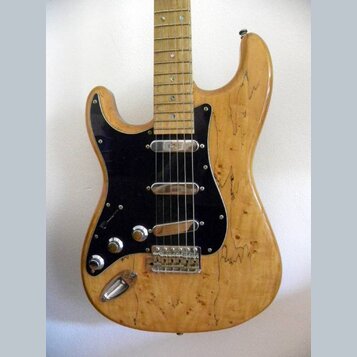 Elektrická kytara s tělem z přírodního dřeva s výraznou kresbou zrn. Má černý pickguard, tři snímače typu single-coil a chromovaný hardware. Na krytc…