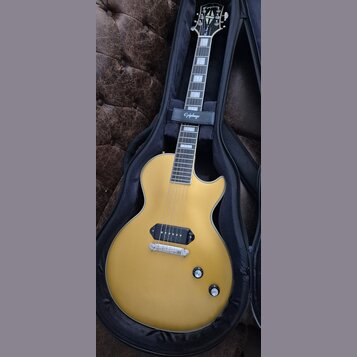 Zlatá elektrická kytara s jedním humbuckerem v pozici kobylky, umístěná v černém obalu. Na hlavě nástroje je bílé logo Epiphone a nápis Les Paul Spec…