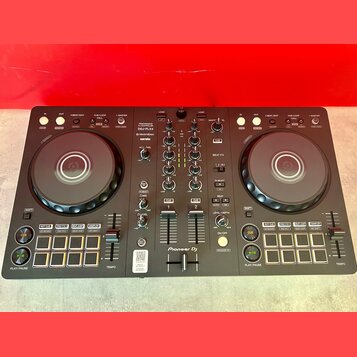 Černý DJ kontrolér s dvěma jog-koly a centrálním mixážním sekcí. Na přístroji jsou nápisy PERFORMANCE DJ CONTROLLER, DDJ-FLX4, rekordbox a serato, v…