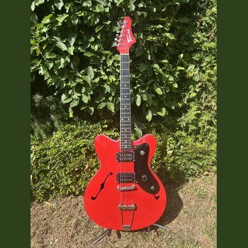 Červená elektrická kytara s polodupatým korpusem a černým pickguardem. Na hlavě hmatníku je bílý nápis "Tonic". Nástroj má dva humbuckery, stříbrný m…