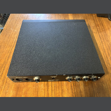 Černý elektronický přístroj s texturovaným povrchem šasi. Na zadní straně jsou nápisy Dynamic MIDI IN, THRU a OUT, REPEAT, POWER oraz LEXICON LXP-1 P…