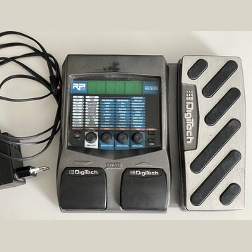 Šedý kytarový procesor s výrazem Digitech RP 250 a nápisem MODELING GUITAR PROCESSOR. Zařízení obsahuje digitální displej, řadu tlačítek pro ovládání…