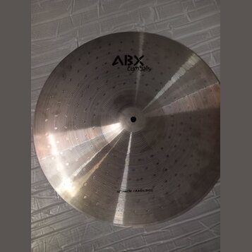 Kovový činel stříbrné barvy s viditelným rýhováním a jamkovaným povrchem. V horní části je černý nápis ABX Cymbals a v dolní části text 16" 46CM CRAS…