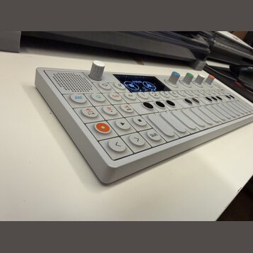 Bílá elektronická klaviatura s kontroléry a displejem. Na ovládacím panelu jsou vidět nápisy JOIN, 1-4 a Shift. Zařízení obsahuje několik bílých tlač…