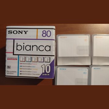 Krabice a čtyři kusy recordable MiniDisc disků značky SONY, model bianca. Na krabici je nápis 80, 10 pack a seznam barev: Marshmallow Peach, Marshmal…