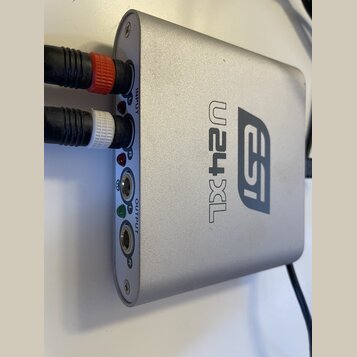 Stříbrný audio rozhraní s kovovým povrchem a logem esi a označením U24XL. Na levém boku jsou vstupy INPUT (L, R) a výstupy OUTPUT (L, R), do kterých…