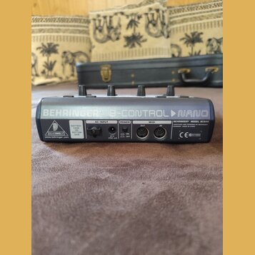 Zadní strana černého MIDI kontroléru s nápisem BEHRINGER B-CONTROL NANO. Na zařízení jsou vidět konektory AC INPUT, POWER a MIDI (OUT, IN), přepínač…