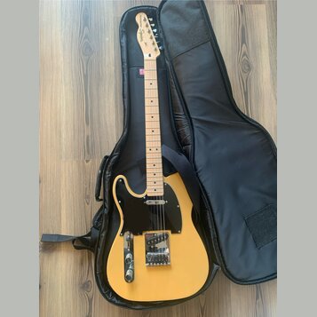 Žlutá elektrická kytara typu Telecaster s černým pickguardem a světle hnědým hmatníkem. Na hlavě je nápis Fender Squier. Kytara leží v černém polstro…