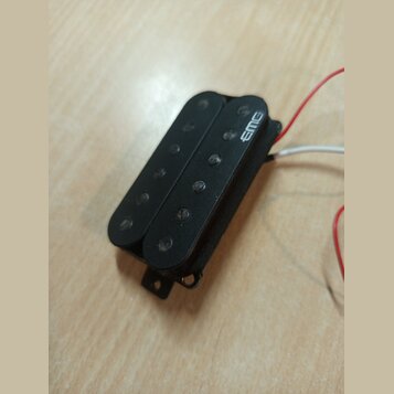 Černý humbucker snímač s plastovým krytem. Na horní části je bílý nápis EMG. Z boku vedou bílé a červené vodiče, spodní část vykazuje drobné známky o…