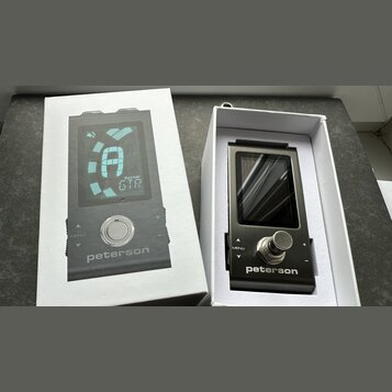 Fotografie zobrazuje digitální ladicí zařízení značky peterson v bílém originálním obalu. Na horním obrázku je vidět displej s nápisem GTR a symbolem…