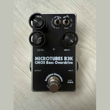 Černý efekt pedál s nápisy MICROTUBES B3K a CMOS Bass Overdrive. Na spodní části je logo Darkglass Electronics a označení napájení 9VDC. Pedál má dva…