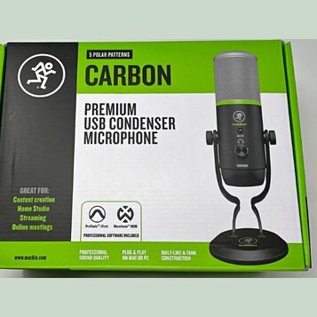 Fotografie znázorňuje krabici od mikrofonu s nápisy CARBON a PREMIUM USB CONDENSER MICROPHONE. Na obalu je zobrazen černý mikrofon s limegreenovým pr…