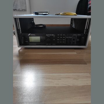 Černý rackový procesor s nápisem FRACTAL AUDIO SYSTEMS a označením Axe-Fx II HD HARMONY PROCESSOR. Zařízení je umístěno v kovovém racku stříbrné barv…