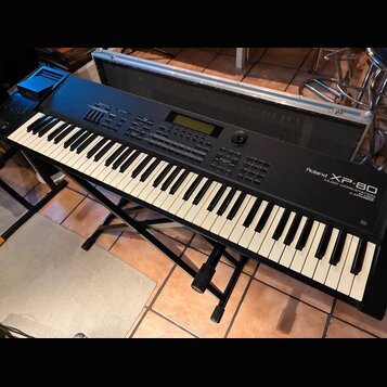 Černý digitální klavír Roland XP-80 Music Workstation na černém kovovém stojanu. Nástroj má standardní klávesnici a horní panel s displejem, tlačítky…