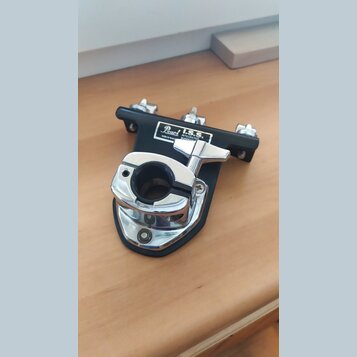 Černý kovový držák s chromovanými prvky a utahovacím šroubem. Na bílém štítku je nápis Pearl I.S.S. INTEGRATED SUSPENSION SYSTEM a drobný text made i…