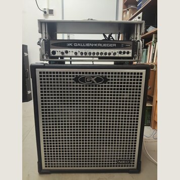 Basový kombozesilovač tvořený dvěma částmi. Horní racková jednotka nese nápis GK GALLIEN-KRUEGER 700RB. Spodní reproduktorová skříň má stříbrnou mříž…