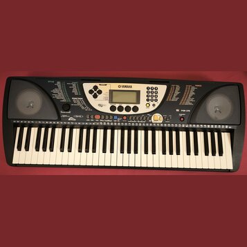 Černý digitální klavír značky YAMAHA, model PSR-270. Nástroj má standardní klávesnici a ovládací panel s displejem, tlačítky pro výběr stylů a hlasů…