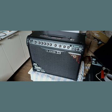 Černý kytarový kombozesilovač s textilní maskou reproduktoru. Na předním panelu je nápis LINE 6 a v dolní části texty 75 Watts, 400+ presets a 12" CE…