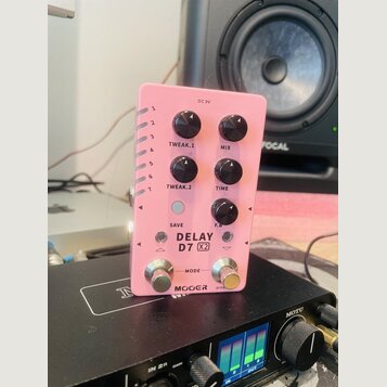 Růžový efekt pedál s nápisy TWEAK.1, MIX, TWEAK.2, TIME, SAVE a F.B. Na spodní části je uveden model DELAY D7 X2 a značka MOER BYPASS. Zařízení má čt…