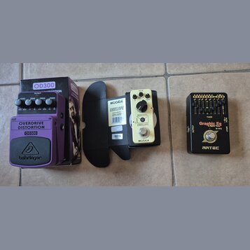 Na fotografii jsou tři kytarové efekty. Vlevo je fialový pedál s nápisy OVERDRIVE DISTORTION, OD300 a značkou behringer, vedle něj je jeho originální…