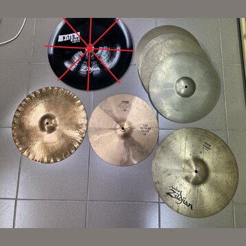 Sestet činelů v různých barvách a velikostech. Černý činel nese nápisy „Pitch Black“ a „Zildjian“. Jeden z mosazných činelů má nápisy „PAISTE“, „404“…