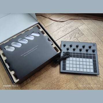 Šedý sampler Novation Circuit Rhythm s mřížkou bílých podsvícených padů a ovládacími knoflíky. V horní části je nápis CIRCUIT RHYTHM a v pravém horní…