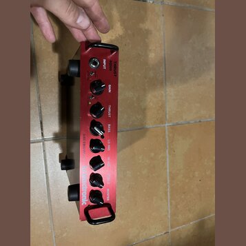 Červený basový zesilovač s nápisy THRUST a BQ500. Na předním panelu jsou ovládací knoflíky s popisky GAIN, THRUST, BASS, LO-MID, HI-MID, TREBLE a MAS…