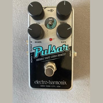 Stompbox efekt s kovovým stříbrným šasi a černým spodním panelem. Na horní části jsou čtyři černé oválné ovladače s popisky VOL, DEPTH, SHAPE a RATE.…