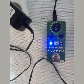 Zelený efekt pedál s nápisy DRUM MACHINE a FLAMMA. Obsahuje jeden ovládací knoflík s označením RHYTHM, dva modré přepínače LEVEL a EQ/SPEED, svítící…