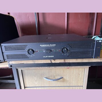 Černý výkonový zesilovač v kovovém šasi s nápisy AMERICAN AUDIO a PROFESSIONAL POWER AMPLIFIER. Na předním panelu je uprostřed označení modelu VLP150…