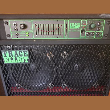 Fotografie zachycuje horní ovládací panel a přední mřížku basového komba. Na zeleném panelu jsou nápisy TRACE ELLIOT, GRAPHIC GP11 PREAMPLIFIER Mk V…