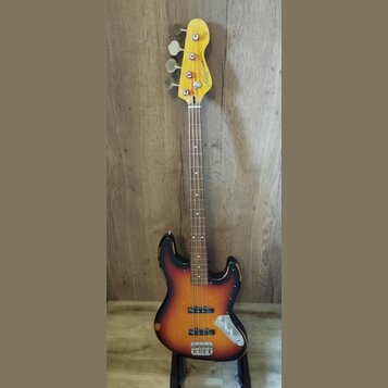 Elektrická basová kytara s korpusem v barevném přechodu od černé přes oranžovou k žluté (sunburst). Na hlavě hmatníku je nápis "Wilkinson ICON Series…