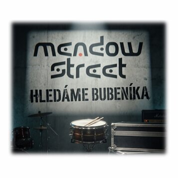 Fotografie zobrazuje buben s položenými paličkami, část činelu na stojanu a černý transportní case. V pozadí je zeď s velkým nápisem „meadow street“…