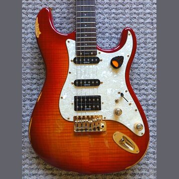 Elektrická kytara s červeně-žlutým sunburst povrchem a bílým perleťovým pickguardem. Na tříech snímačích je uveden nápis LEVINSON. Kytara má zlatý ha…