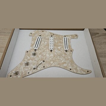 Bíle perleťový pickguard pro elektrickou kytaru s třemi snímači. Na krajních snímačích je nápis „Suhr Classic“. Vybavení zahrnuje přepínač, tři poten…