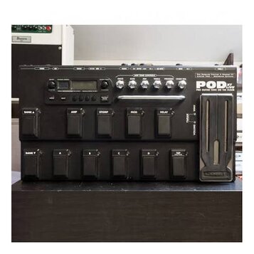 Černý kytarový procesor Line 6 POD XT Live. Na horním panelu jsou ovládací knofíky, displej a nápisy AMP TONE CONTROLS, DRIVE, BASS, MID, TREBLE, PRE…