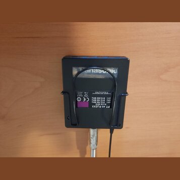 Černý plastový bezdrátový vysílač s připojeným mikrofonem. Na spodní straně je fialová nálepka s nápisy PT 40 FLEXX, Band 40/G, ch1 812.700 MHz, ch2…