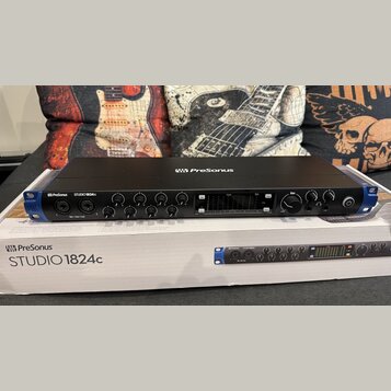 Černý rackový zvukový interface PreSonus STUDIO 1824c s modrými bočními elementy. Na předním panelu jsou umístěny ovládací knofíky, dva kombinované v…