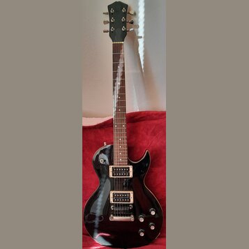 Černá elektrická kytara s tmavým hnedým hmatníkem a bílými tečkovanými značkami poloh. Nástroj má dva humbuckery s krémovými rámečky, stříbrný kobyln…