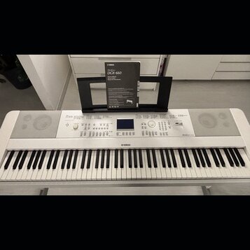 Bílá digitální klaviatura značky YAMAHA, model DGX-660. Nástroj má v horní části ovládací panel s displejem, tlačítky a knoflíky, vpravo je nápis Dig…